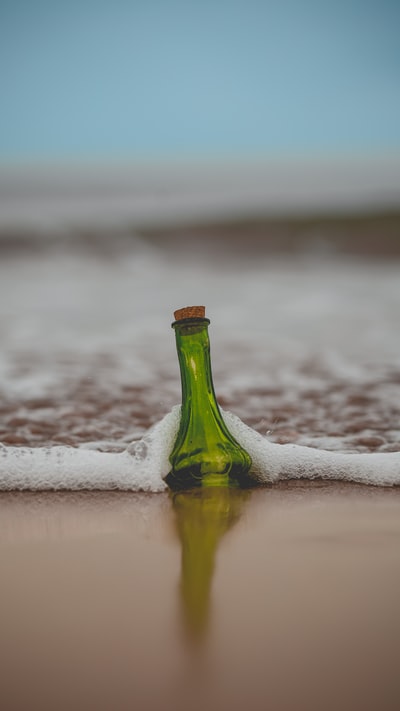 绿色玻璃瓶子和软木塞盖在岸上
